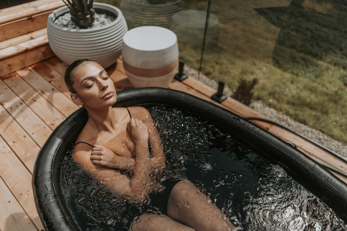 Femme détendue dans le bain froid OASIS sur une terrasse en bois