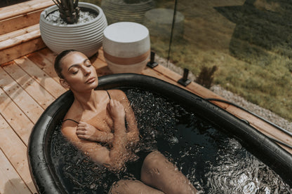 Femme détendue dans le bain froid OASIS sur une terrasse en bois